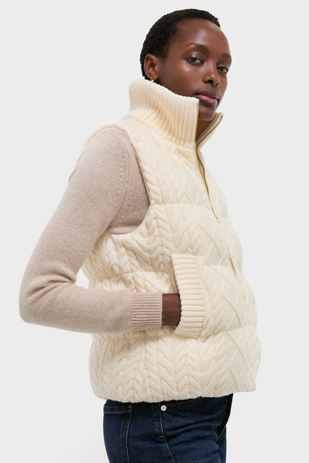 Model in Egret Irina Cable Knit Gilet, showcasing classic cable-knit design and effortless style with padded sections, ribbed collar, and two-way zip, paired with jeans for a high-end look.