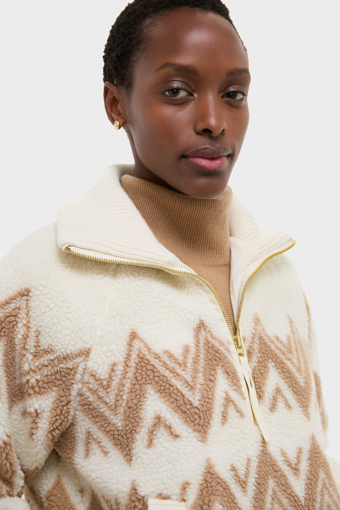 Model in Egret Hendrik Half Zip Sherpa jacket, featuring a classic geometric pattern and gold zip, layered over a turtleneck for an effortless, high-end winter look.