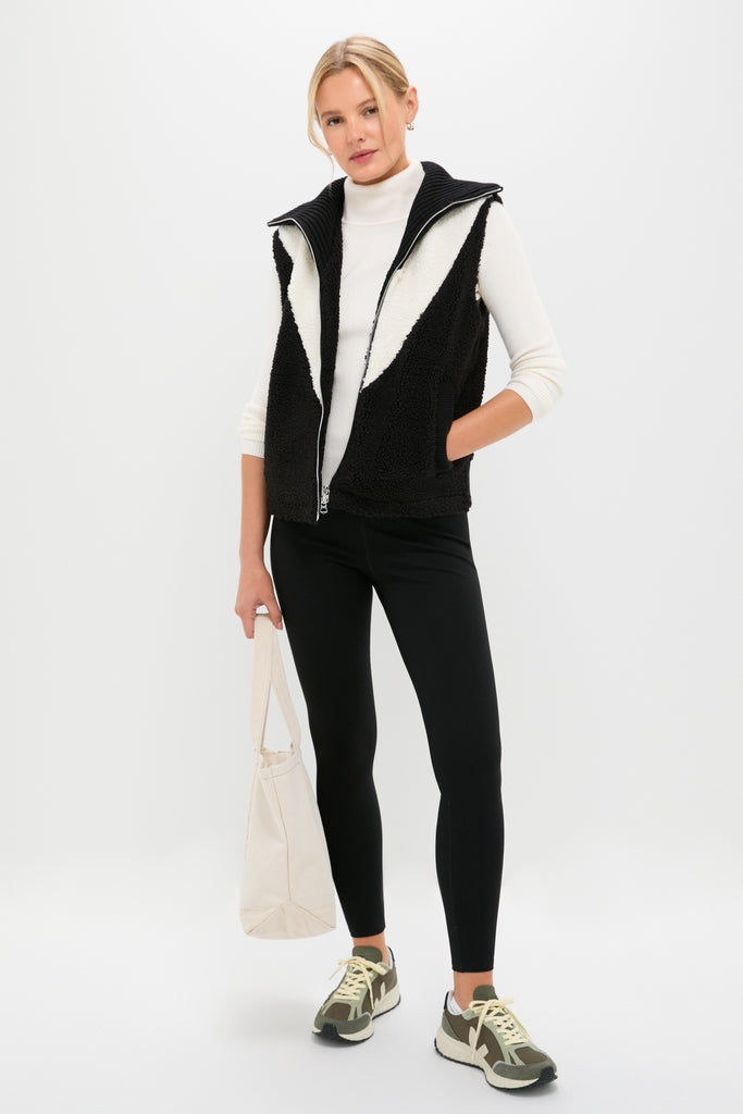 Model wearing Black Caspian Sherpa Gilet, classic and high-end with a ribbed collar, styled effortlessly with a casual, sporty-chic outfit for a fun, confident look.
