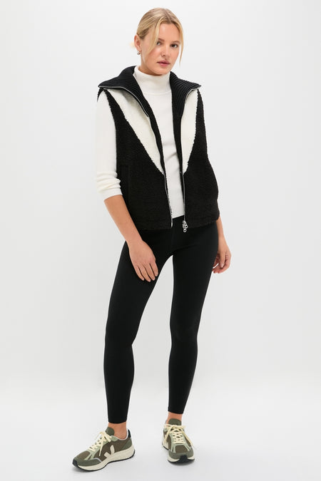 Model wearing the classic Black Caspian Sherpa Gilet over a fitted turtleneck, paired with leggings and lace-up sneakers, showcasing an effortlessly cool and fun high-end style.