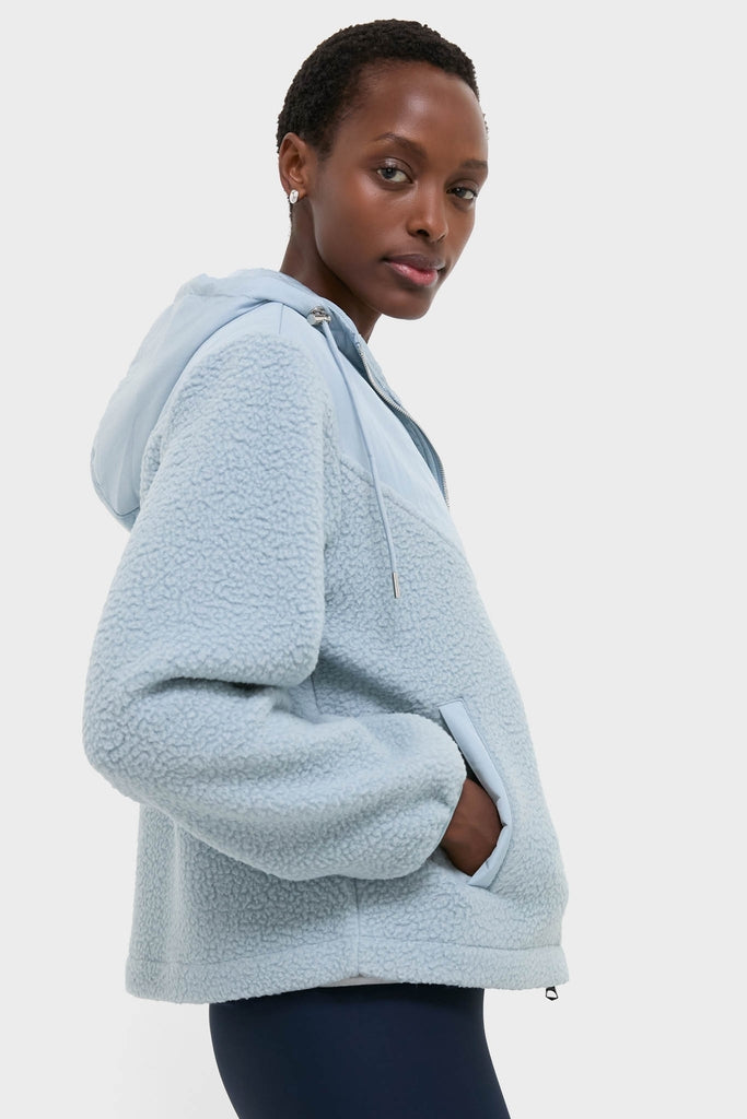 Woman in profile wearing an Ashley Blue Rosia Fleece Hoodie, an effortlessly classic sherpa-style jacket with a hood, paired with dark leggings for a fun, high-end look.