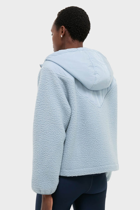 Person in classic Ashley Blue Rosia Fleece Hoodie, featuring a quilted back, large hood, and boxy fit, embodying effortless, high-end style with leggings.