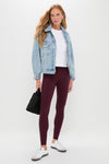 Model in Winetasting High Rise Long Compression Spandex MacKenzie Legging, light-wash denim jacket, and sneakers, holding a black tote, showcasing a classic, effortless athleisure look.