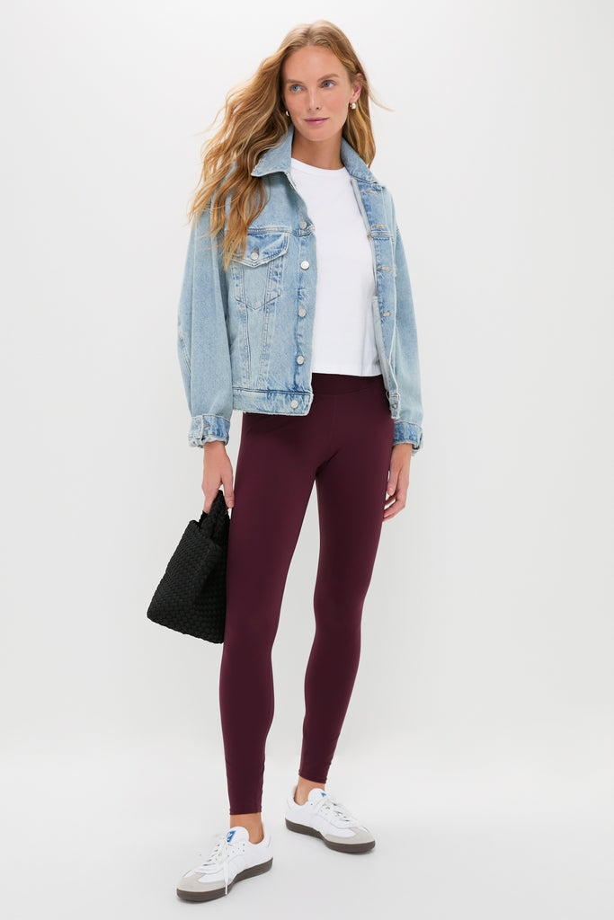 Model in Winetasting High Rise Long Compression Spandex MacKenzie Legging, light-wash denim jacket, and sneakers, holding a black tote, showcasing a classic, effortless athleisure look.