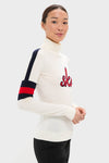 Model in classic Snow White Neve Wool Sweater, featuring bold sleeve stripes and ski detail, showcasing effortless, high-end alpine style.