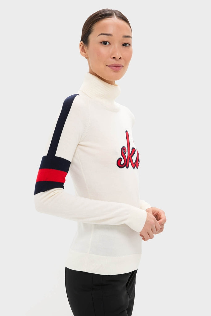 Model in classic Snow White Neve Wool Sweater, featuring bold sleeve stripes and ski detail, showcasing effortless, high-end alpine style.