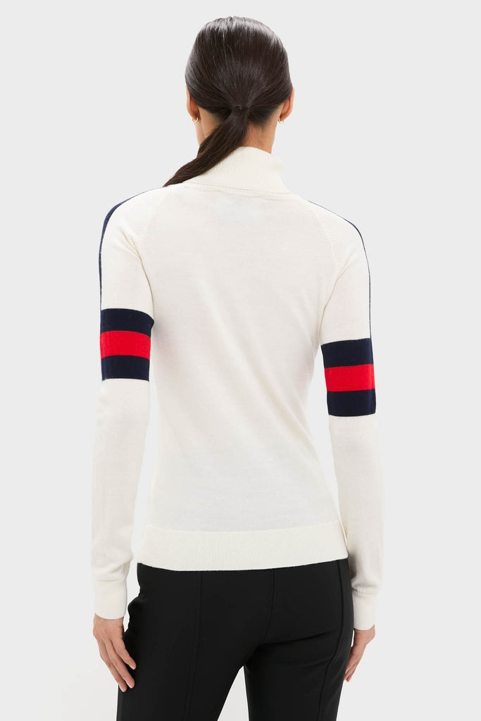 Back view of a woman in a classic Snow White Neve Wool Sweater with navy and red arm stripes, embodying effortless, high-end alpine style.