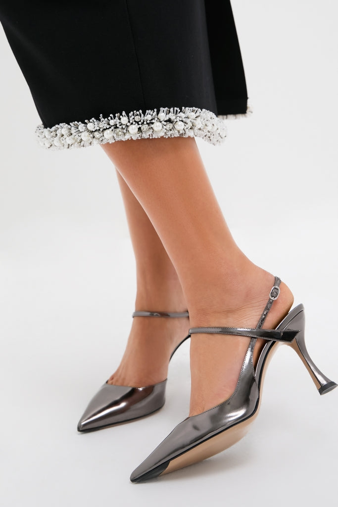 Woman’s legs in Black Idina Midi Skirt with white-beaded hem, paired with metallic-gunmetal slingback heels, showcasing a classic, effortless, and high-end fashion style.