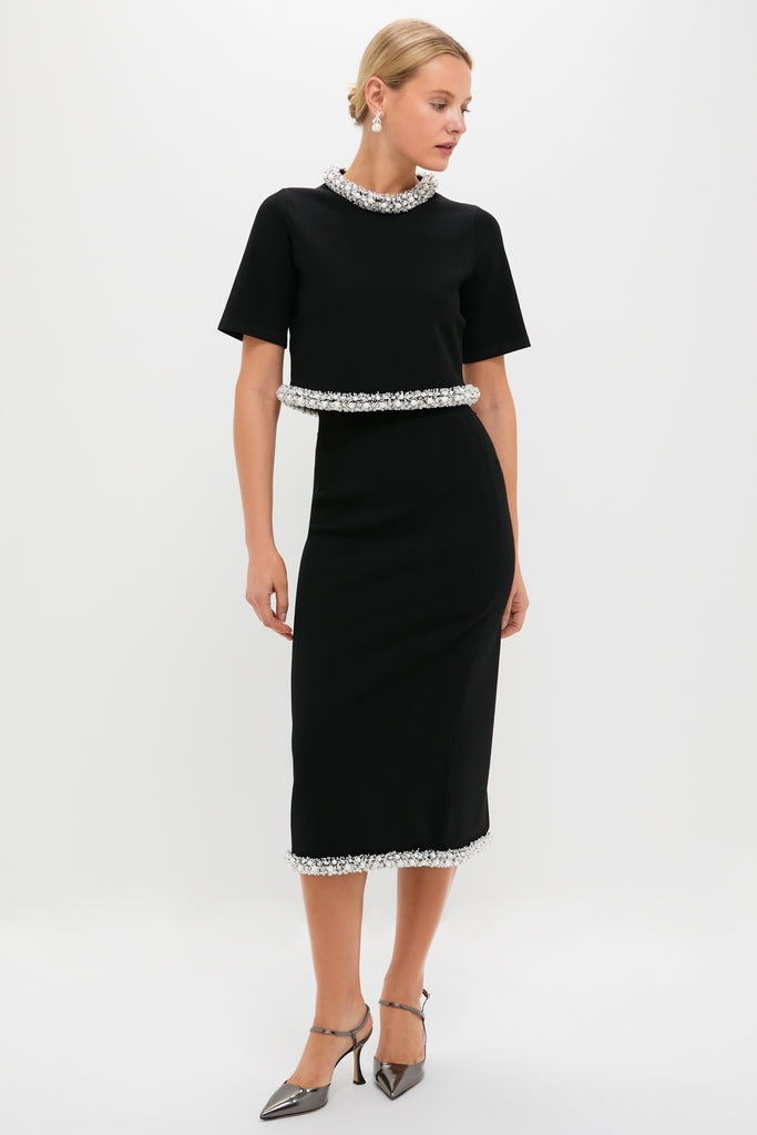 Model showcases the Black Idina Midi Skirt, a classic high-waisted pencil design with white trim, paired effortlessly with a cropped top and metallic slingback pumps for a high-end, fun look.