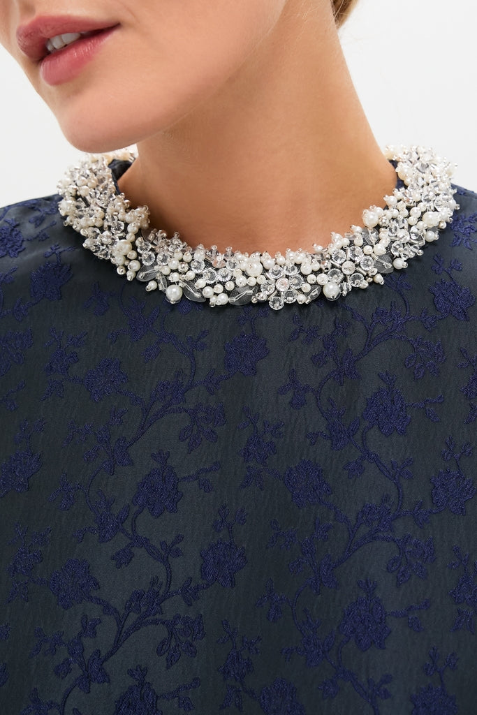 Close-up of a woman's lower face and neck, showcasing the classic Midnight Alison Short Sleeve Mini Dress, paired with an effortless, high-end pearl and crystal necklace.