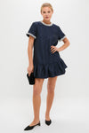 Model in the classic Midnight Alison Short Sleeve Mini Dress with white-beaded trim, holding a black clutch. Effortless and fun, embodies high-end style with a ruffled mini silhouette.