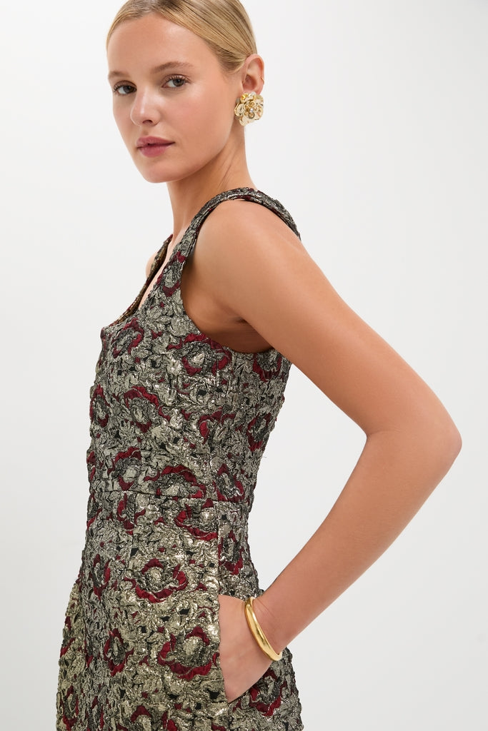 Young woman in a classic, high-end Ruby Multi Ravenna Midi Dress with metallic brocade, showcasing effortless style. Accessorized with a chunky gold bangle and floral earring.