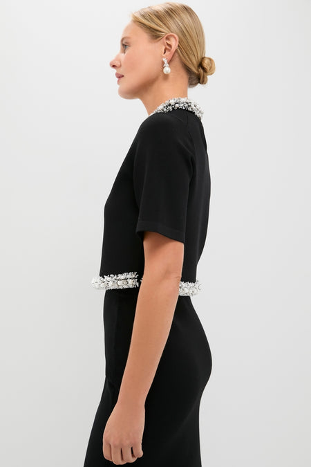 Model in a classic Black Ozelle Short Sleeve Crewneck Top, adorned with white bead trim, exudes effortless elegance and high-end style, paired with pearl drop earrings.