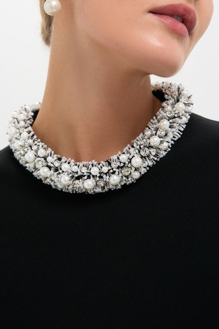 Woman wearing Black Ozelle Short Sleeve Crewneck Top with a high-end, beaded collar trim featuring pearls and crystals, paired with a dangling pearl earring for an effortless, classic look.