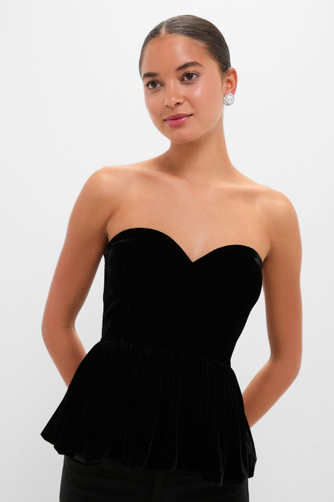 Young woman in a classic Black Velvet Peplum Strapless Tudor Blouse with a sweetheart neckline and flared hem, embodying effortless elegance and high-end fashion.