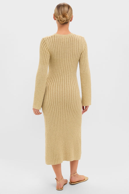 Person in a classic Gold Knit Amanyara Maxi Dress, showcasing its effortless, form-fitting design with long sleeves. Paired with thong-style sandals for a fun, high-end look.