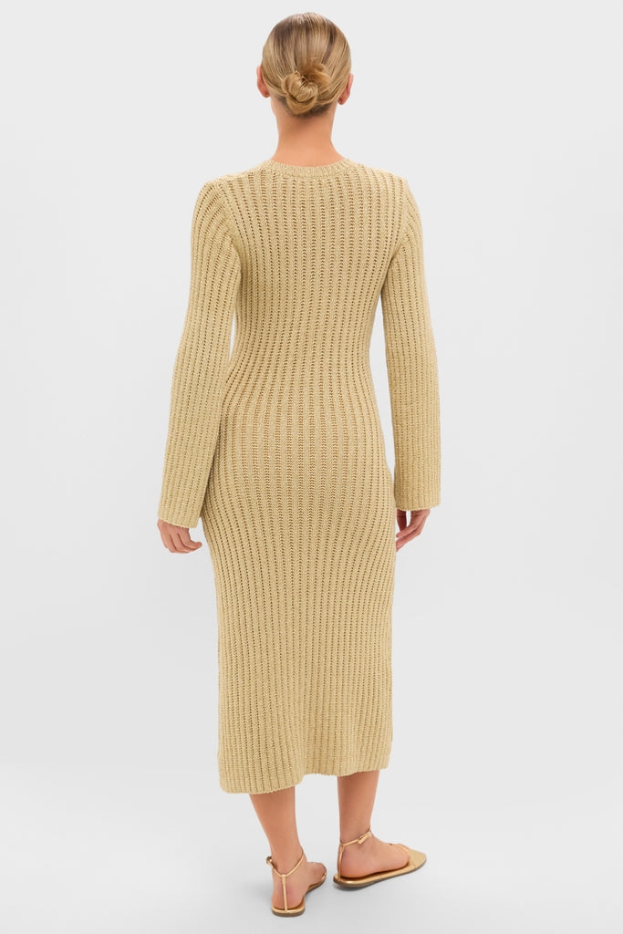 Person in a classic Gold Knit Amanyara Maxi Dress, showcasing its effortless, form-fitting design with long sleeves. Paired with thong-style sandals for a fun, high-end look.