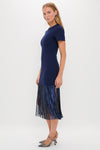 Woman models the classic Navy Sequin Fringe Stevie Midi Dress with an effortless fit, featuring a fitted top and fun fringe hem, paired with high-end metallic slingback shoes.