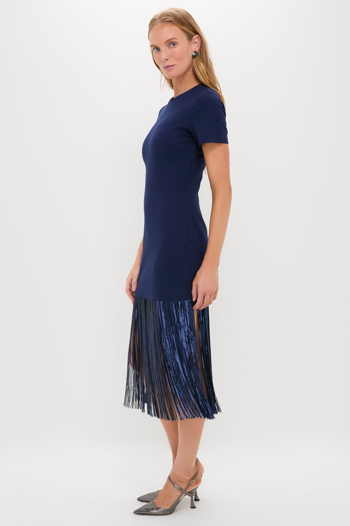 Woman models the classic Navy Sequin Fringe Stevie Midi Dress with an effortless fit, featuring a fitted top and fun fringe hem, paired with high-end metallic slingback shoes.
