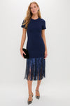Woman in Navy Sequin Fringe Stevie Midi Dress, a classic, high-end piece with fringe detailing, holding an oval clutch, embodying effortless elegance and fun style.