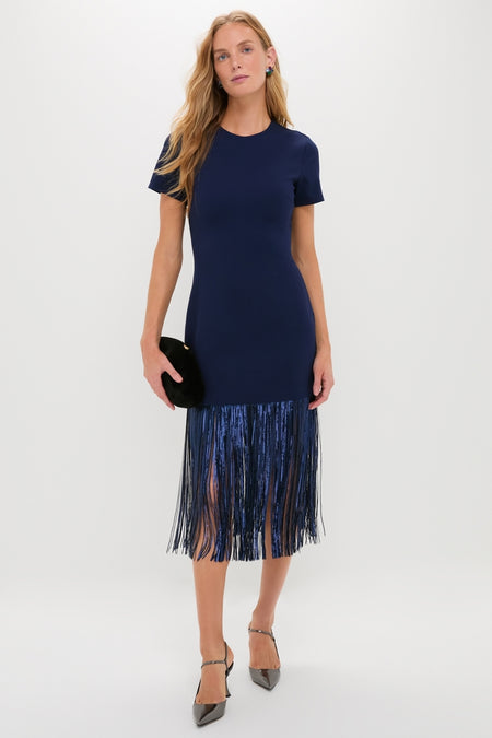 Woman in Navy Sequin Fringe Stevie Midi Dress, a classic, high-end piece with fringe detailing, holding an oval clutch, embodying effortless elegance and fun style.