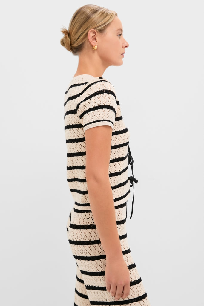 Woman in classic Black & Tan Stripe Portimao Top with short sleeves, V-neckline, and center-front bows, styled effortlessly with matching high-waisted pants.