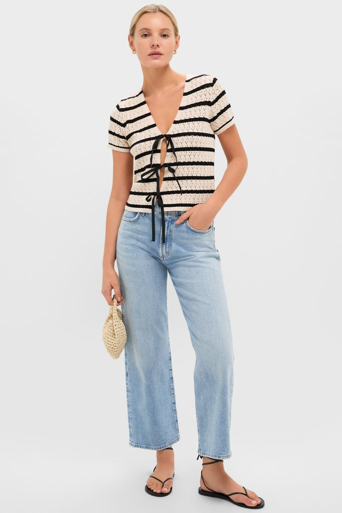 Model wearing the classic Black & Tan Stripe Portimao Top with center-front bows, paired with high-waisted jeans and a woven pouch for an effortless, high-end look.