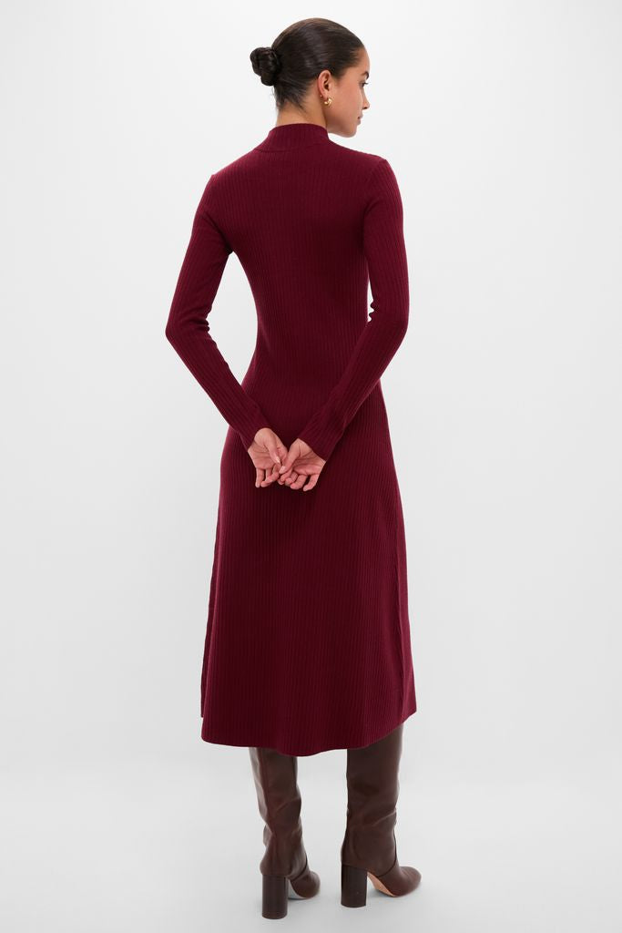 Woman in Oxblood Knit Conrad Midi Swing Dress, showcasing its classic mock turtleneck and ribbed texture, paired with high-end knee-high brown leather boots for an effortless, fun style.