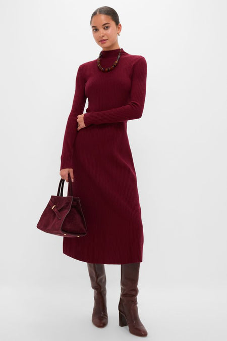 Model wearing the classic Oxblood Knit Conrad Midi Swing Dress with a mock neckline, paired effortlessly with a chunky necklace, matching suede handbag, and high-end knee-high leather boots.