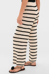 Black & Tan Stripe Portimao Pants, featuring classic wide-leg design, horizontal stripes, and ribbed waistband, paired with black thong sandals for an effortlessly chic, high-end look.