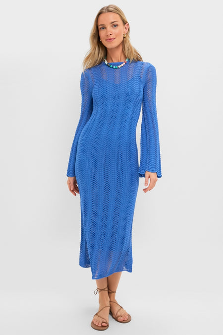 Model wears the Cerulean Knit Comporta Midi Dress, a classic, effortless, open-knit maxi with long sleeves, paired with a beaded necklace and strappy sandals.