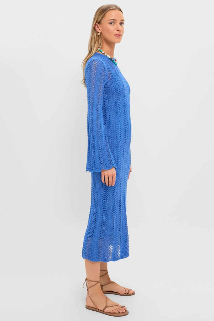 Woman in a Cerulean Knit Comporta Midi Dress with bell sleeves, styled with tan lace-up sandals, a chunky bead necklace, and gold hoops, exuding an effortless, high-end look.