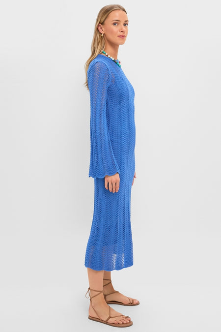 Woman in a Cerulean Knit Comporta Midi Dress with bell sleeves, styled with tan lace-up sandals, a chunky bead necklace, and gold hoops, exuding an effortless, high-end look.