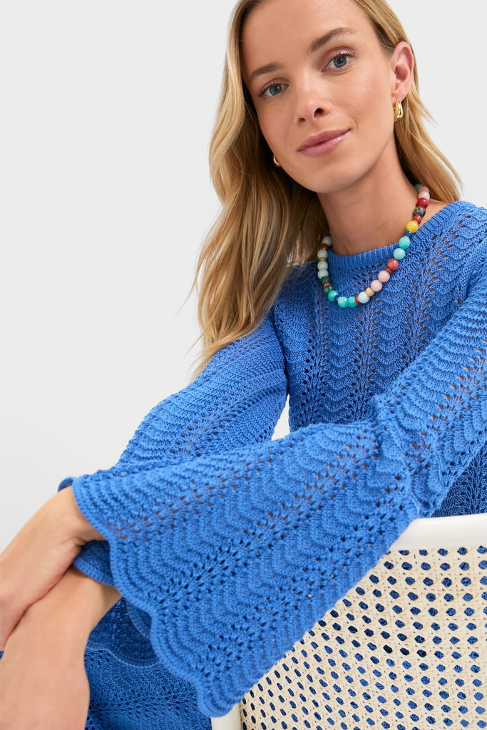 Young woman in an effortless, classic cobalt-blue crochet sweater with scalloped bell sleeves, embodying the high-end, fun style of the Cerulean Knit Comporta Midi Dress.