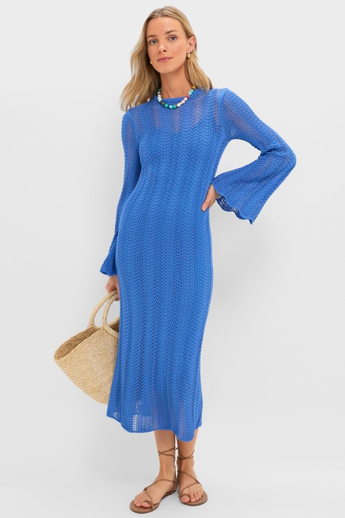 Model wearing the classic Cerulean Knit Comporta Midi Dress, featuring bell sleeves and an open-knit design, styled with an effortless straw tote and fun, chunky necklace.