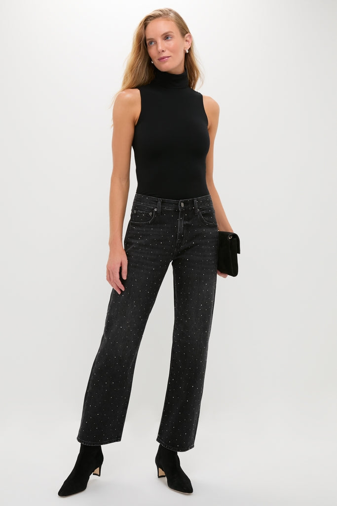 Model in chic Silver Screen Lexi Bowed Straight jeans, styled with rhinestones, paired with a sleeveless black turtleneck bodysuit, exuding an effortless, high-end, and classic look.