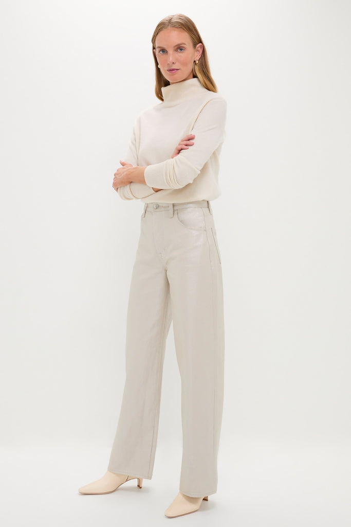 Woman in a classic, high-end Champagne Luster Tate High Rise Bowed Wide Leg denim, embodying effortless elegance and fun style with a light-cream turtleneck.