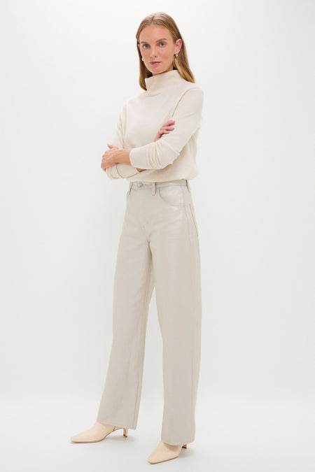 Woman in a classic, high-end Champagne Luster Tate High Rise Bowed Wide Leg denim, embodying effortless elegance and fun style with a light-cream turtleneck.