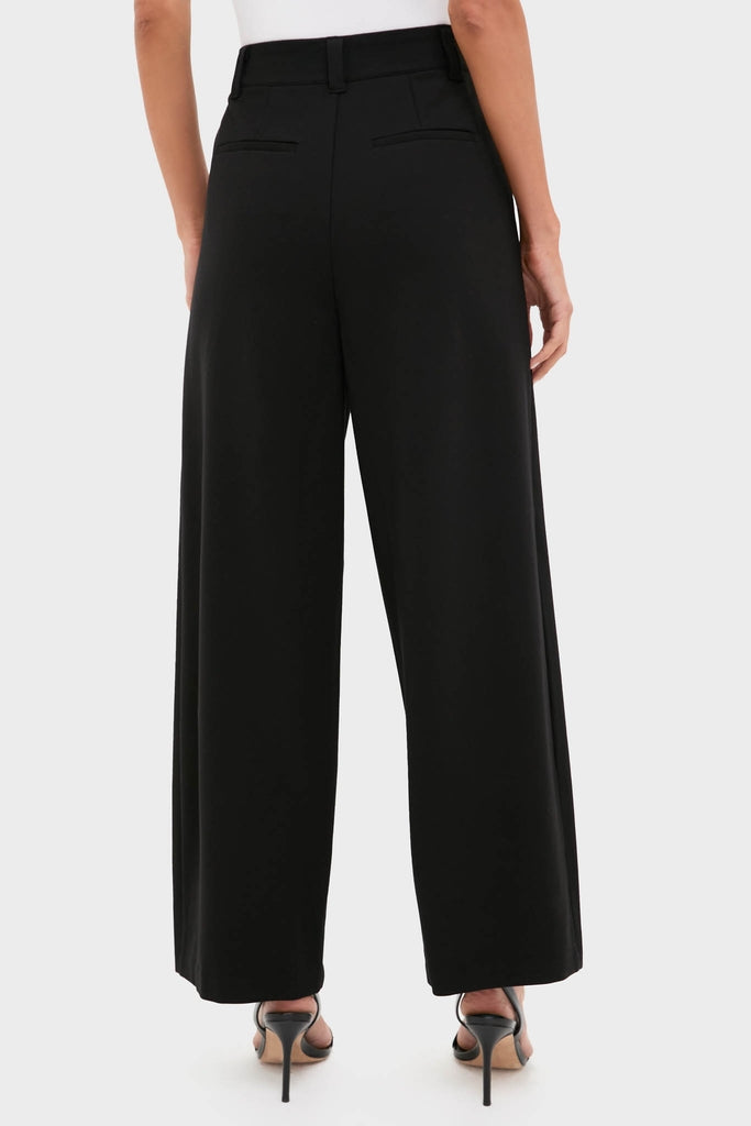 Back view of a model in Night Out Eden Pleated Ponte Trouser, showcasing classic, effortless styling with high-waisted, wide-leg silhouette, paired with strappy sandals for a high-end, fun look.