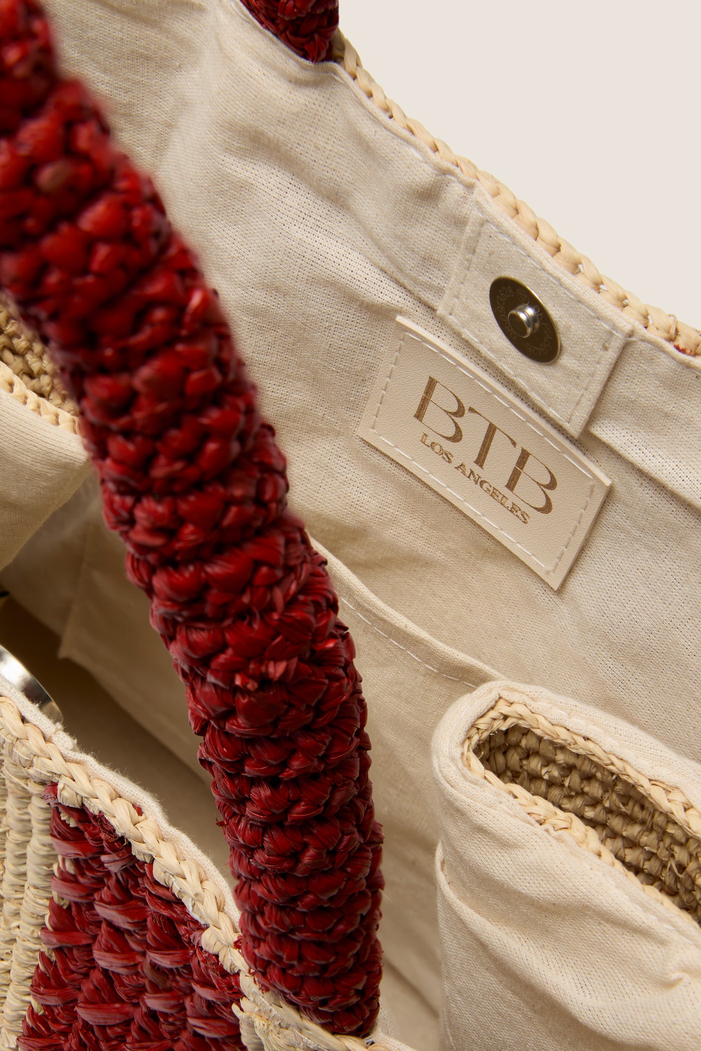 Natural and Rust Serena Large Striped Tote with braided red handles, beige raffia body, interior label BTB Los Angeles, and a practical snap-fastener. Classic, effortless, high-end design.