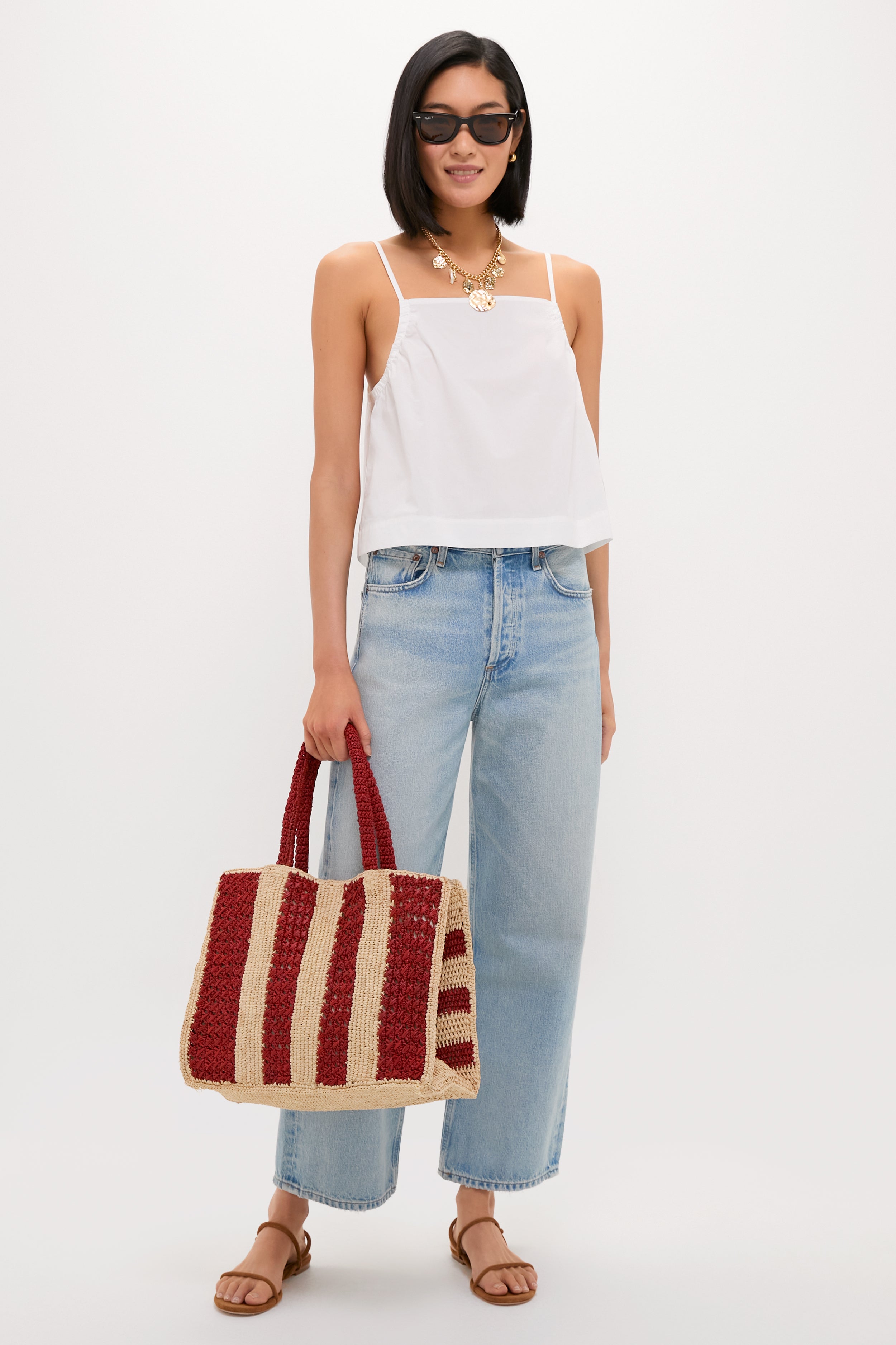 Woman holding the Natural and Rust Serena Large Striped Tote, showcasing its classic, handwoven design and effortless, high-end style with a winged silhouette, perfect for fun, casual outings.