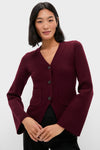 Woman in Claret Aeron V-Neck Cardigan with patch pockets, button placket, and flared sleeves. An effortlessly chic, classic layering piece embodying high-end comfort and style.