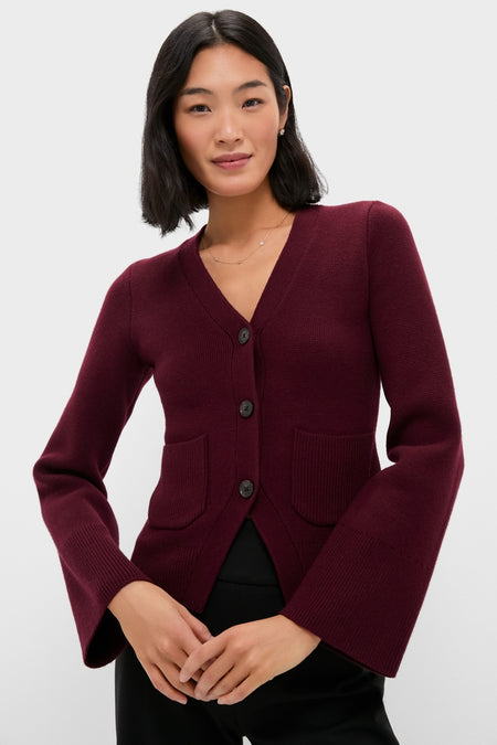 Woman in Claret Aeron V-Neck Cardigan with patch pockets, button placket, and flared sleeves. An effortlessly chic, classic layering piece embodying high-end comfort and style.