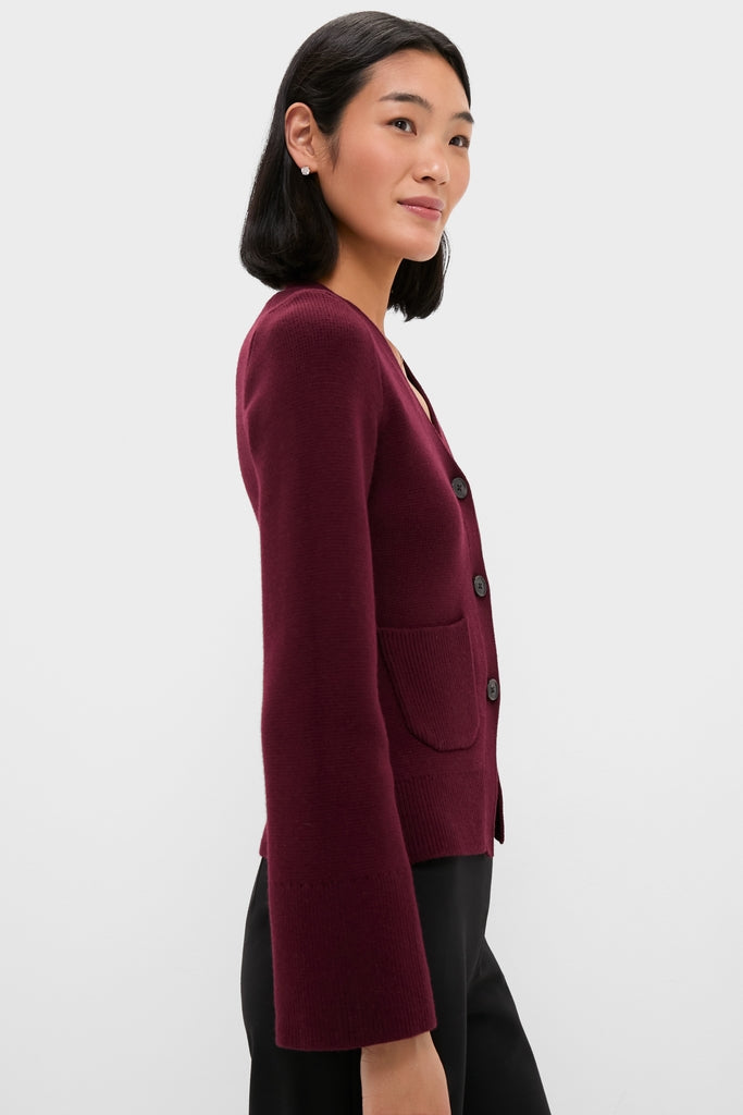 Model in profile wearing Claret Aeron V-Neck Cardigan with classic button-front, patch pocket, and slightly flared sleeves. Effortlessly chic, embodying high-end, fun style.