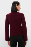 Woman wearing Claret Aeron V-Neck Cardigan with classic button-front, showcasing effortless style. Perfect high-end layering piece for a fun, confident look.
