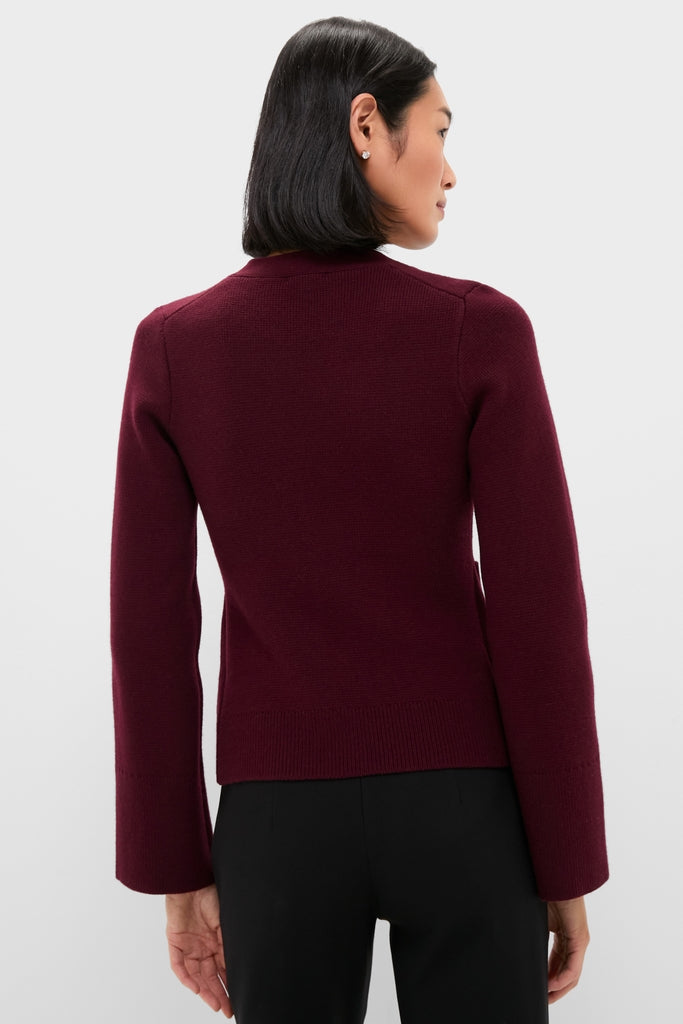 Woman wearing Claret Aeron V-Neck Cardigan with classic button-front, showcasing effortless style. Perfect high-end layering piece for a fun, confident look.