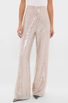 Woman wearing Champagne Sequin Tatum Pants, featuring a high-rise, wide-leg design with light-champagne sequins, paired with a white top and heels, exuding classic, effortless elegance.