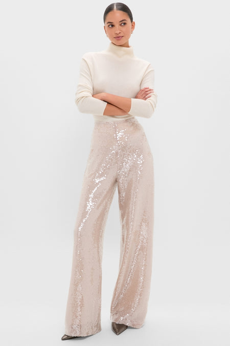 Model in classic, high-end Champagne Sequin Tatum Pants with high-rise, wide-leg design. Paired with a cream turtleneck, conveying an effortless, fun, and elegant style.