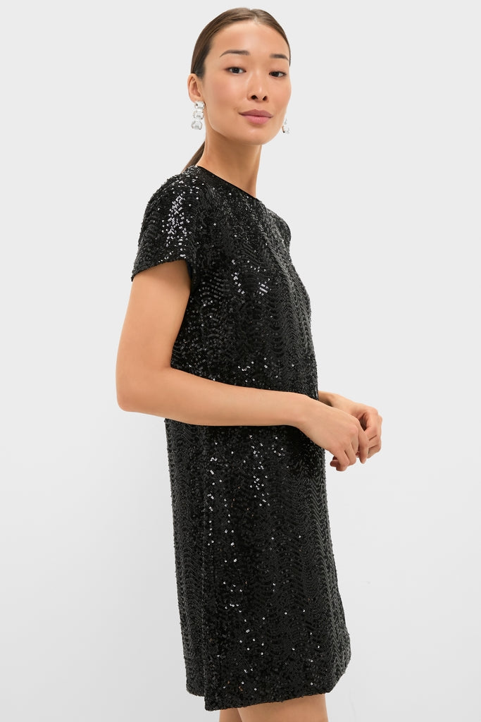 Model wearing the Black Sequin Roya Swing Mini Dress, a classic, high-end shift with an effortless sparkle and fun, chic vibe, complemented by statement drop earrings.