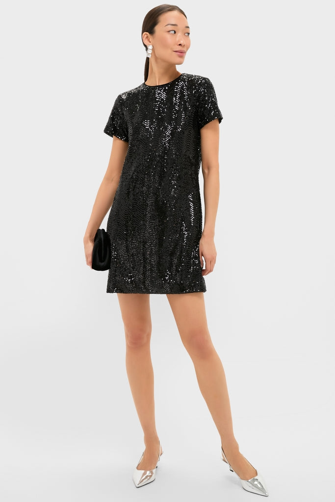 Woman in Black Sequin Roya Swing Mini Dress, holding a black clutch, styled with silver heels and statement earrings, showcasing a classic, effortless, and fun party-ready look.